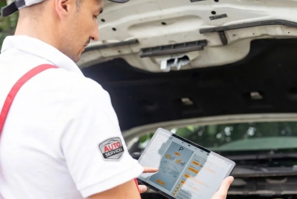 Mecânico usando tablet na oficina ao lado do carro